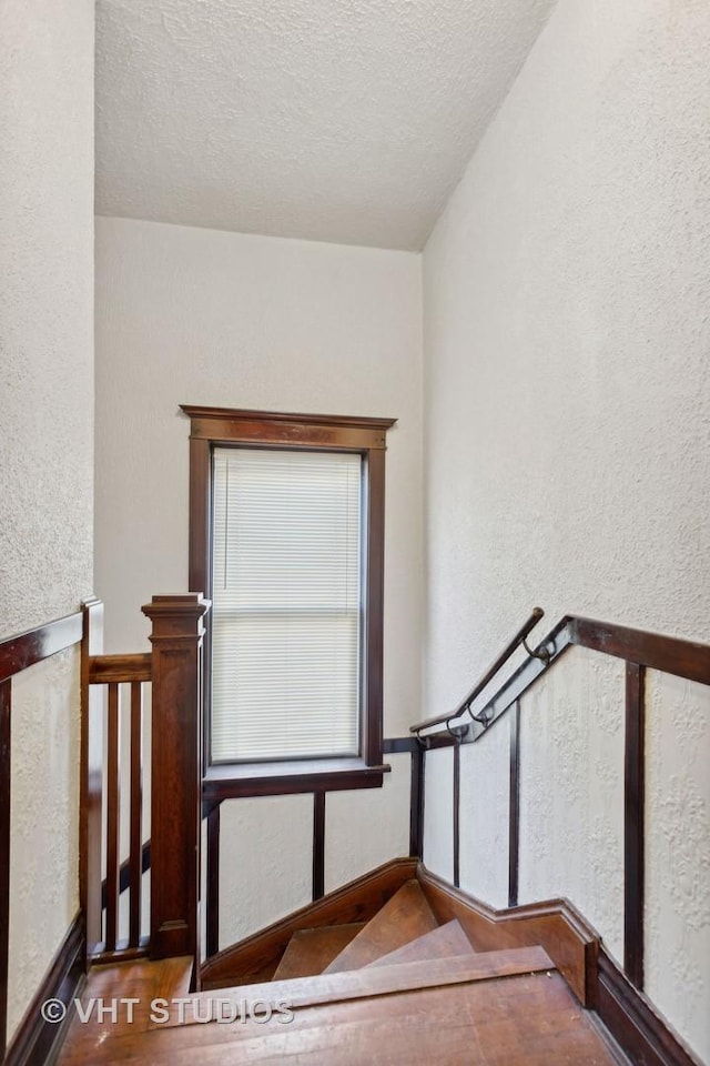 stairs featuring wood-type flooring and a textured ceiling