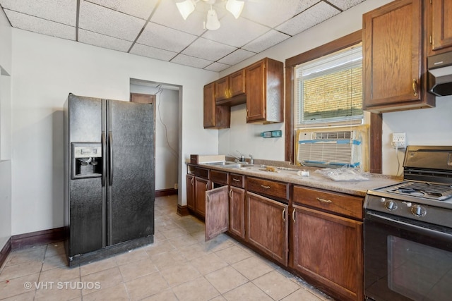 kitchen with a drop ceiling, sink, a wall mounted air conditioner, light tile patterned floors, and black appliances