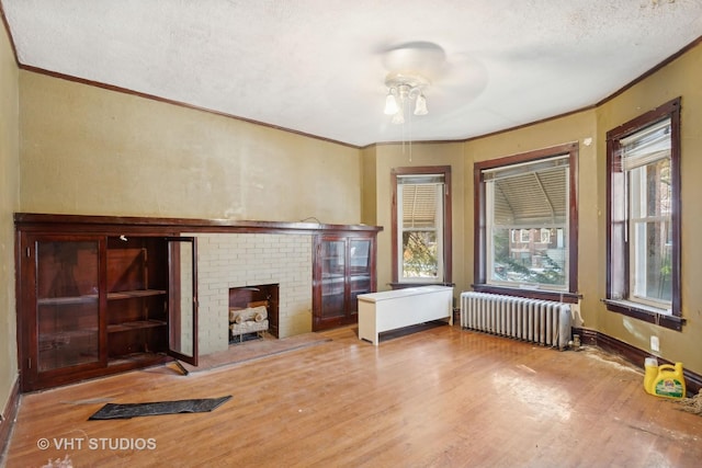 unfurnished living room with light hardwood / wood-style floors, plenty of natural light, radiator, and ceiling fan