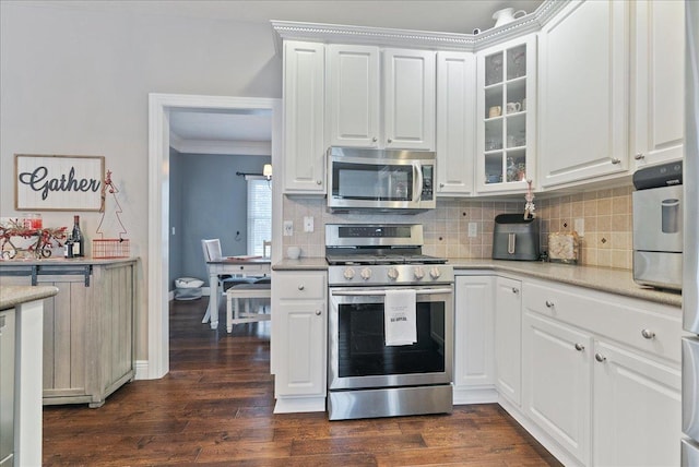 kitchen with dark wood-type flooring, stainless steel appliances, decorative backsplash, white cabinets, and ornamental molding