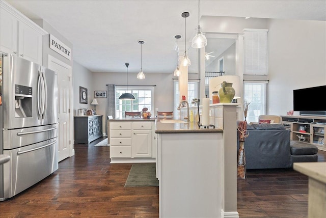 kitchen with dark wood-type flooring, sink, stainless steel fridge with ice dispenser, decorative light fixtures, and white cabinetry