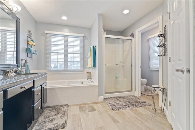 full bathroom featuring plus walk in shower, wood-type flooring, vanity, and toilet