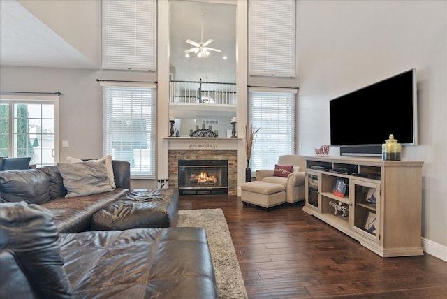 living room with ceiling fan, a fireplace, a high ceiling, and dark hardwood / wood-style floors