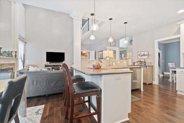 kitchen featuring a breakfast bar, sink, hanging light fixtures, dark hardwood / wood-style flooring, and kitchen peninsula