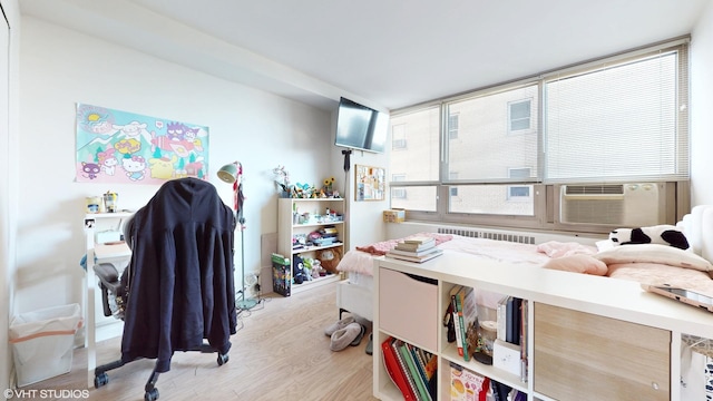 bedroom with light hardwood / wood-style flooring and radiator heating unit