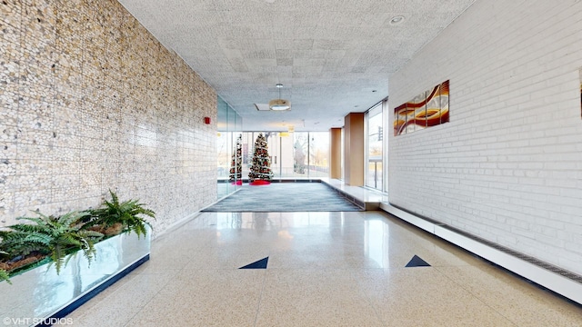 hall with baseboard heating and brick wall