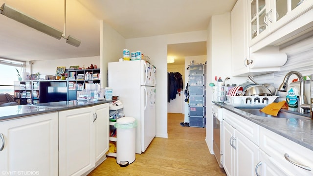 kitchen with white refrigerator, light hardwood / wood-style floors, sink, and white cabinetry