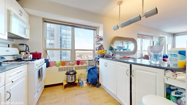 kitchen featuring white cabinets, light wood-type flooring, white appliances, and pendant lighting