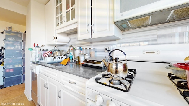 kitchen with white cabinets, light wood-type flooring, and sink