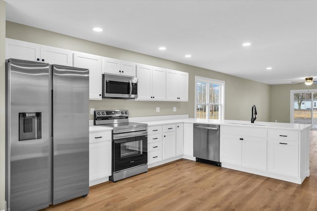 kitchen with a wealth of natural light, sink, white cabinets, kitchen peninsula, and stainless steel appliances