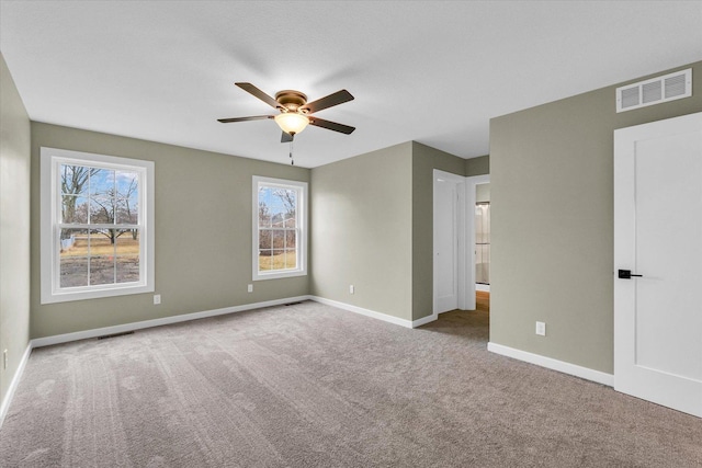 carpeted empty room with ceiling fan and a wealth of natural light