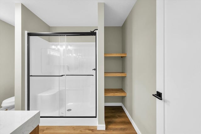 bathroom with hardwood / wood-style flooring, toilet, and an enclosed shower