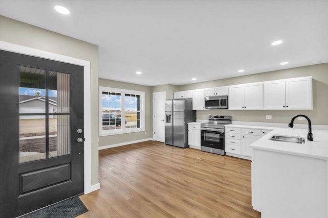 kitchen featuring sink, light hardwood / wood-style flooring, white cabinets, and appliances with stainless steel finishes