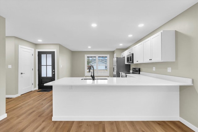 kitchen with white cabinetry, sink, stainless steel appliances, and kitchen peninsula