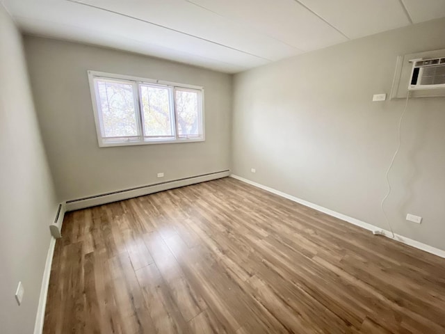 empty room with hardwood / wood-style floors, a wall mounted air conditioner, and a baseboard radiator