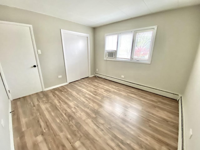 unfurnished bedroom with baseboard heating and light hardwood / wood-style flooring