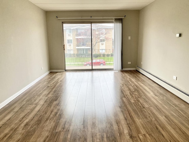 unfurnished room featuring baseboard heating and hardwood / wood-style floors