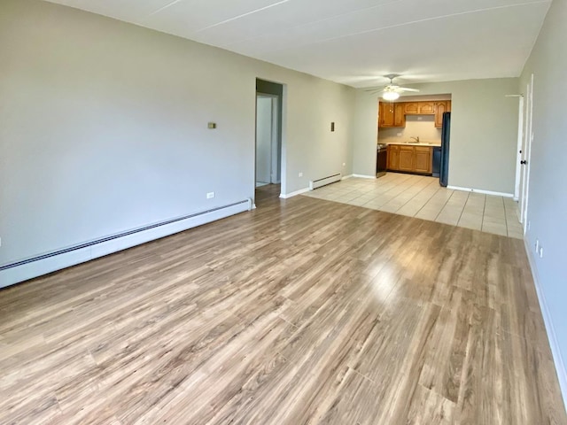 unfurnished living room with ceiling fan, light wood-type flooring, sink, and a baseboard heating unit