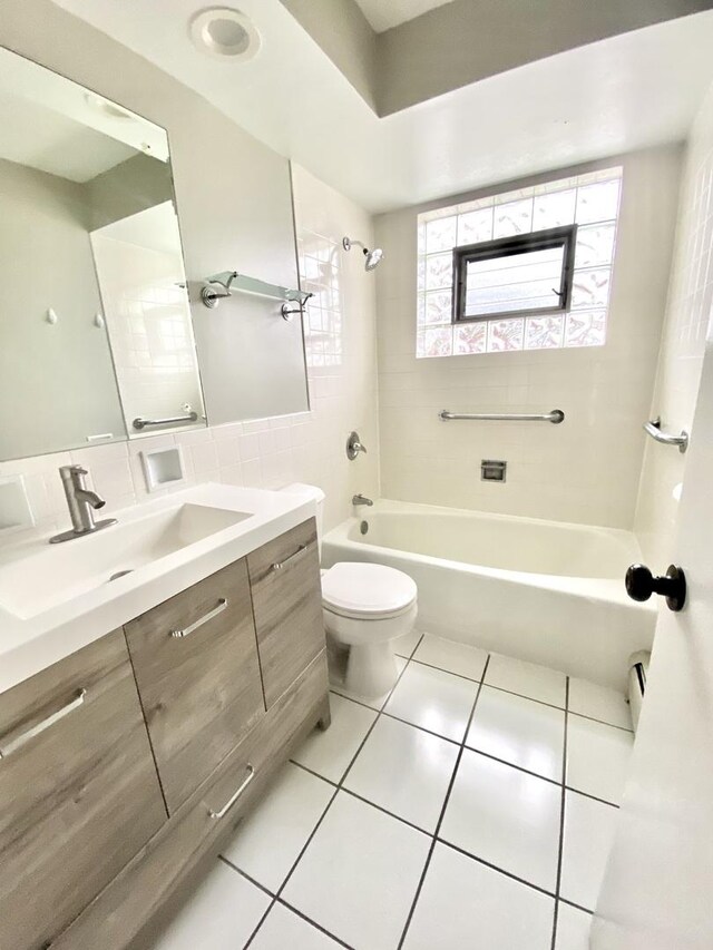 full bathroom with tile patterned floors, vanity, tiled shower / bath combo, and toilet