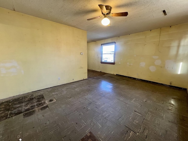 unfurnished room with ceiling fan and a textured ceiling