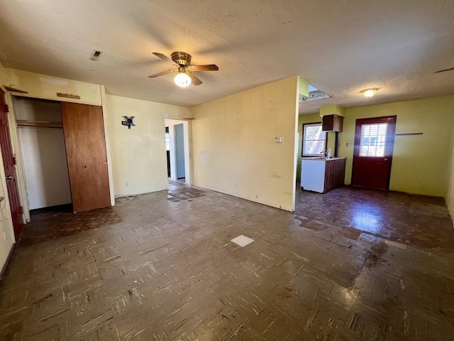 interior space with ceiling fan and a textured ceiling