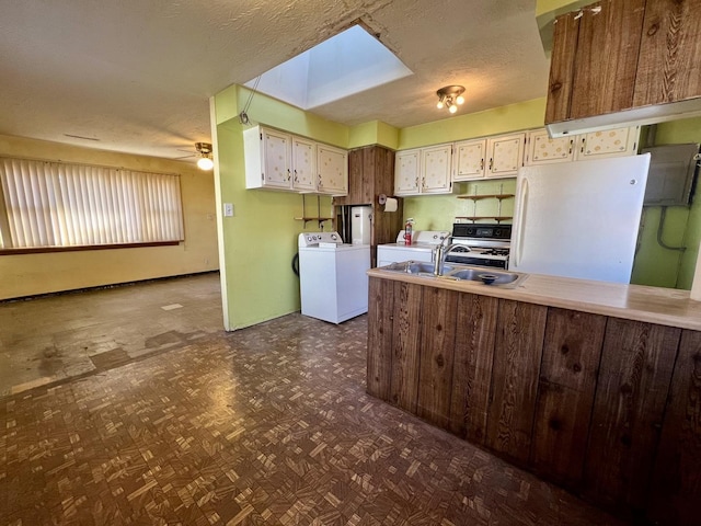 kitchen with kitchen peninsula, a skylight, ceiling fan, sink, and white fridge