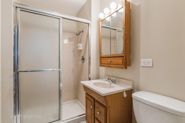 bathroom with a shower stall, toilet, and vanity