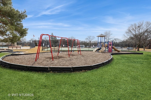 communal playground featuring a lawn and fence