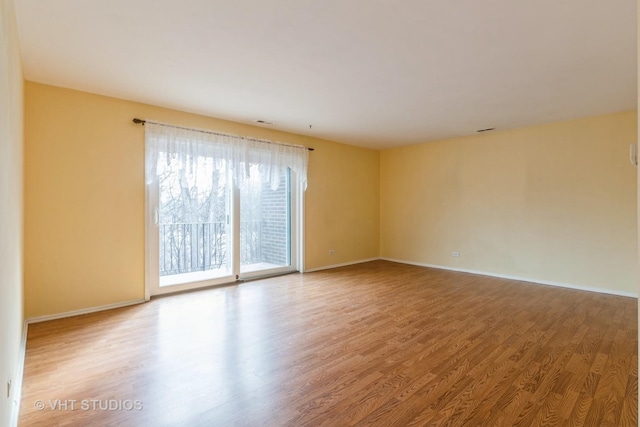 spare room featuring baseboards and wood finished floors