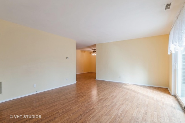 spare room with light wood finished floors, baseboards, visible vents, and a ceiling fan