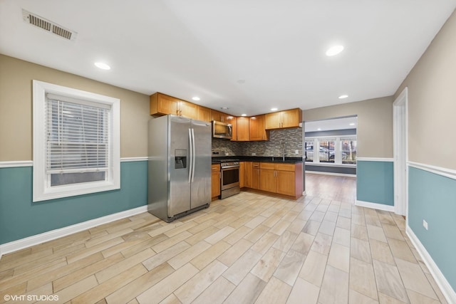 kitchen featuring backsplash, sink, stainless steel appliances, and light hardwood / wood-style floors