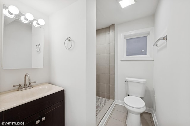 bathroom with a tile shower, tile patterned flooring, vanity, and toilet