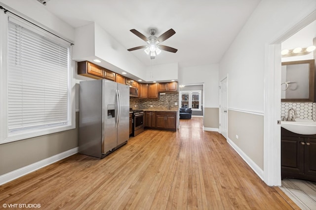 kitchen with appliances with stainless steel finishes, backsplash, light hardwood / wood-style flooring, and sink