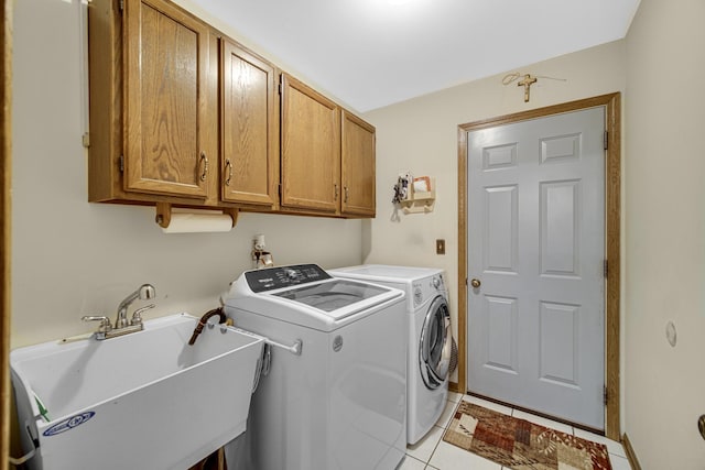 laundry area featuring washer and clothes dryer, cabinets, light tile patterned floors, and sink