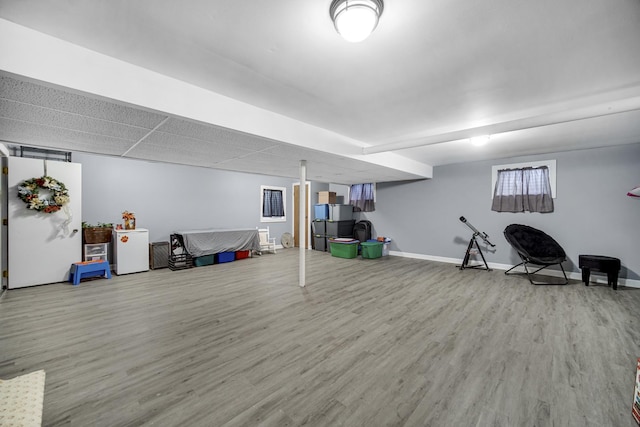 basement featuring fridge and light hardwood / wood-style flooring