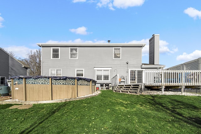 rear view of house featuring a swimming pool side deck and a lawn