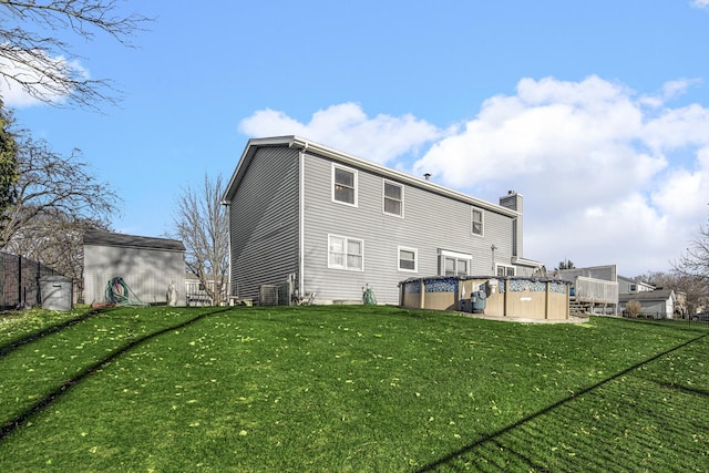 back of property featuring central AC and a lawn