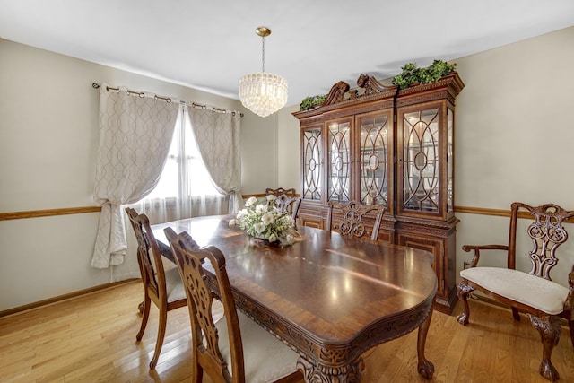 dining area with light hardwood / wood-style floors and an inviting chandelier