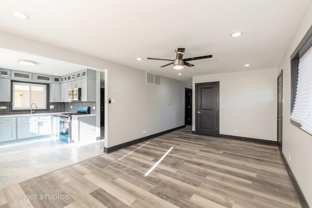 interior space featuring tasteful backsplash, ceiling fan, stainless steel appliances, and light hardwood / wood-style floors