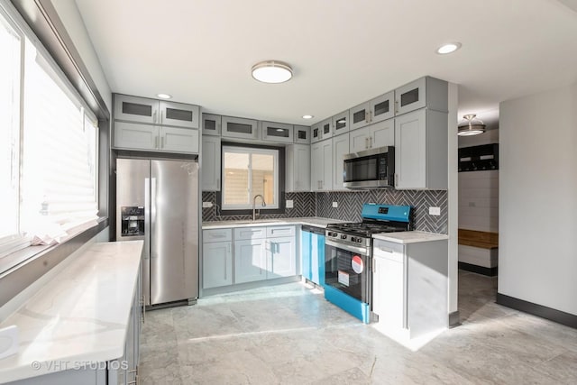 kitchen featuring decorative backsplash, light stone countertops, sink, and appliances with stainless steel finishes