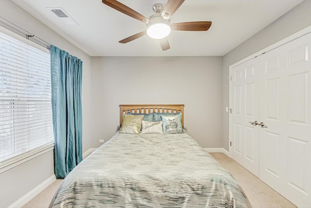 bedroom with ceiling fan, light colored carpet, and a closet