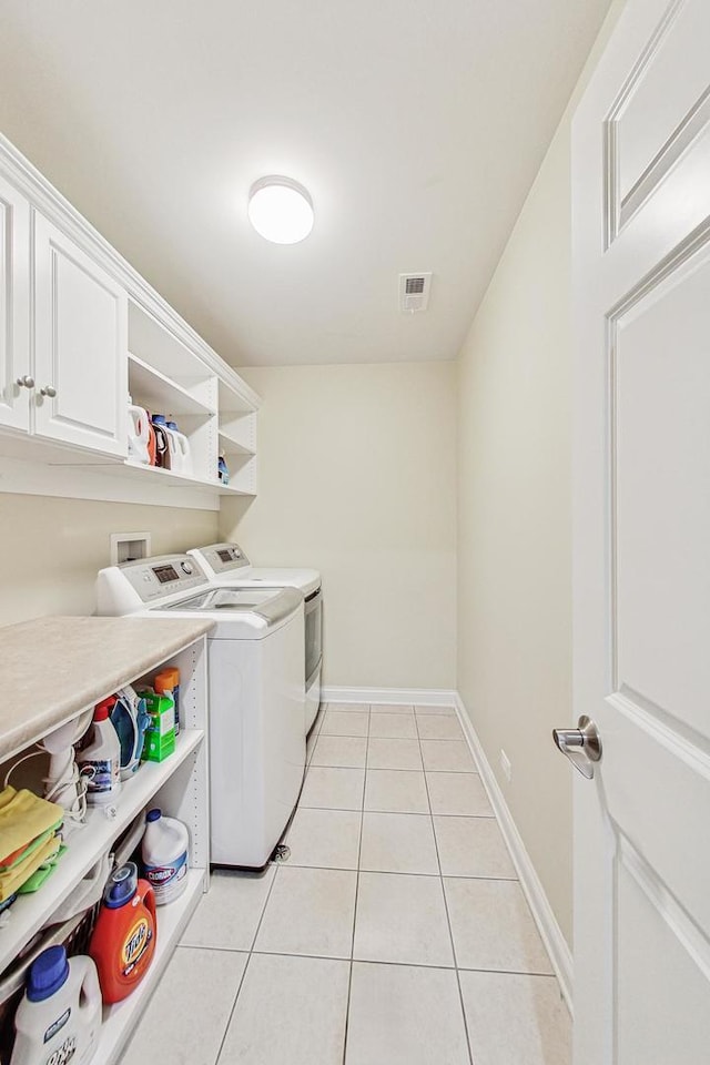 laundry room featuring cabinets, light tile patterned floors, and washing machine and clothes dryer