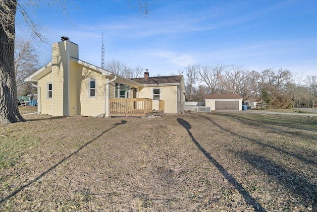 view of front of house with a wooden deck, an outbuilding, a front yard, and a garage