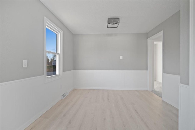 unfurnished room featuring light hardwood / wood-style flooring and a textured ceiling