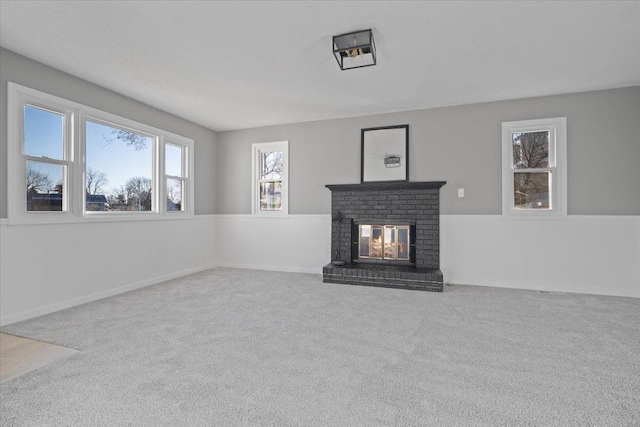 unfurnished living room with light carpet and a brick fireplace