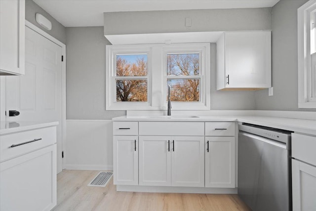 kitchen with white cabinetry, dishwasher, light hardwood / wood-style floors, and sink