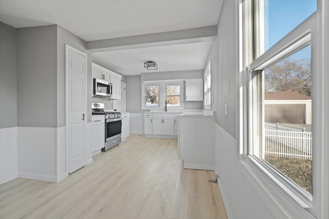 kitchen with white cabinets, light wood-type flooring, sink, and appliances with stainless steel finishes