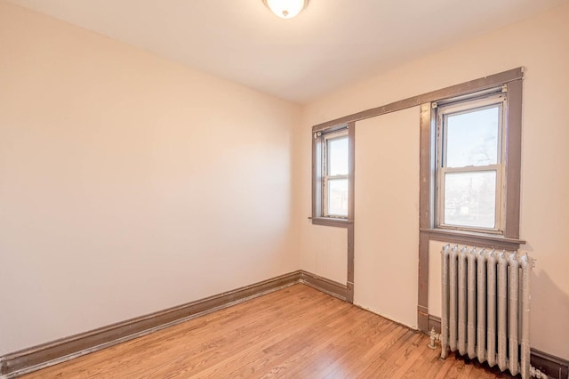 spare room with radiator heating unit and light hardwood / wood-style flooring