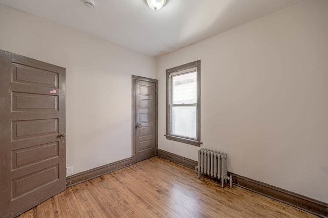 spare room featuring radiator heating unit and light hardwood / wood-style floors