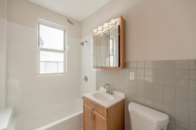 full bathroom featuring tiled shower / bath, vanity, toilet, and tile walls